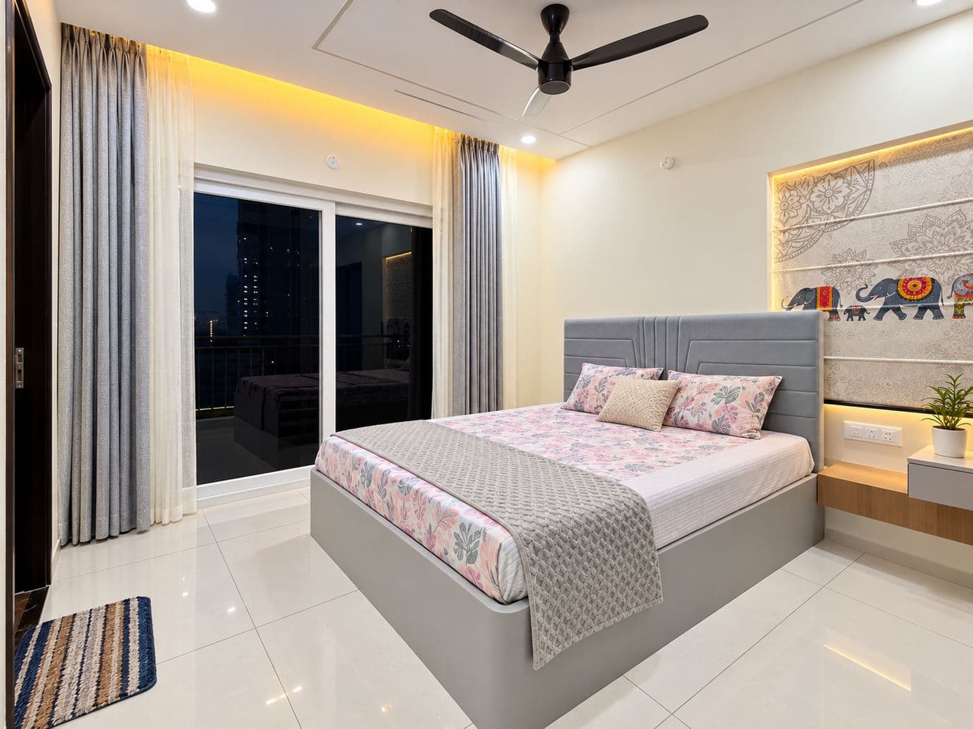 Bedroom with a grey bed, panelled headboard wall and cove lighting