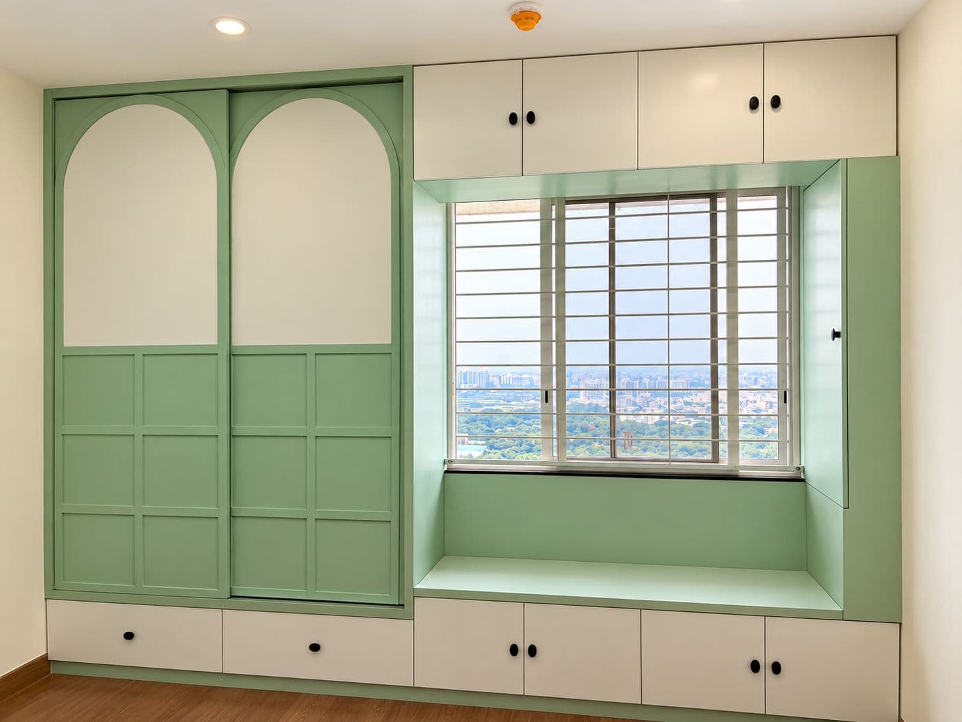 Green wardrobe with arched panels and a window seat with storage drawers