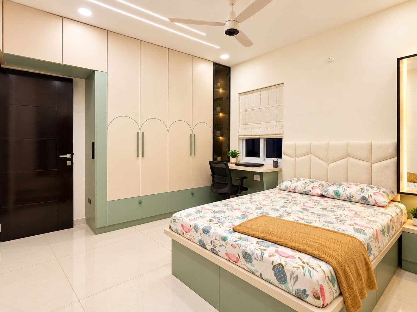 Bedroom with an upholstered headboard and a cream and sage-green wardrobe